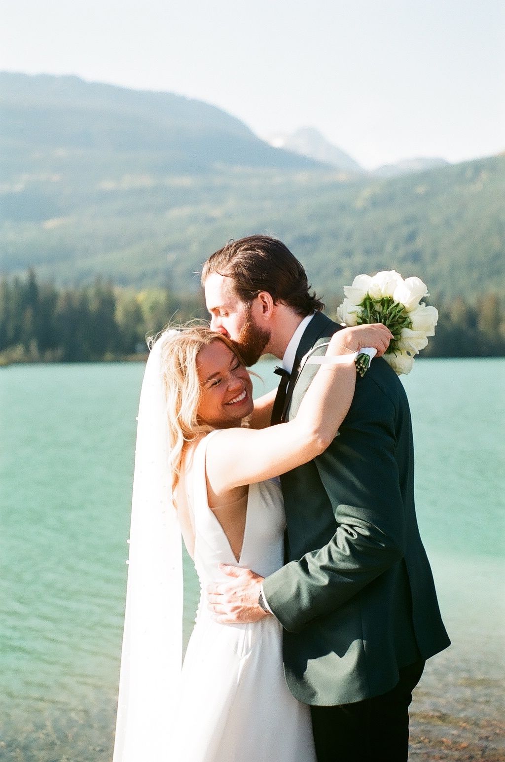 Intimate wedding moment captured against a stunning mountain lake backdrop.