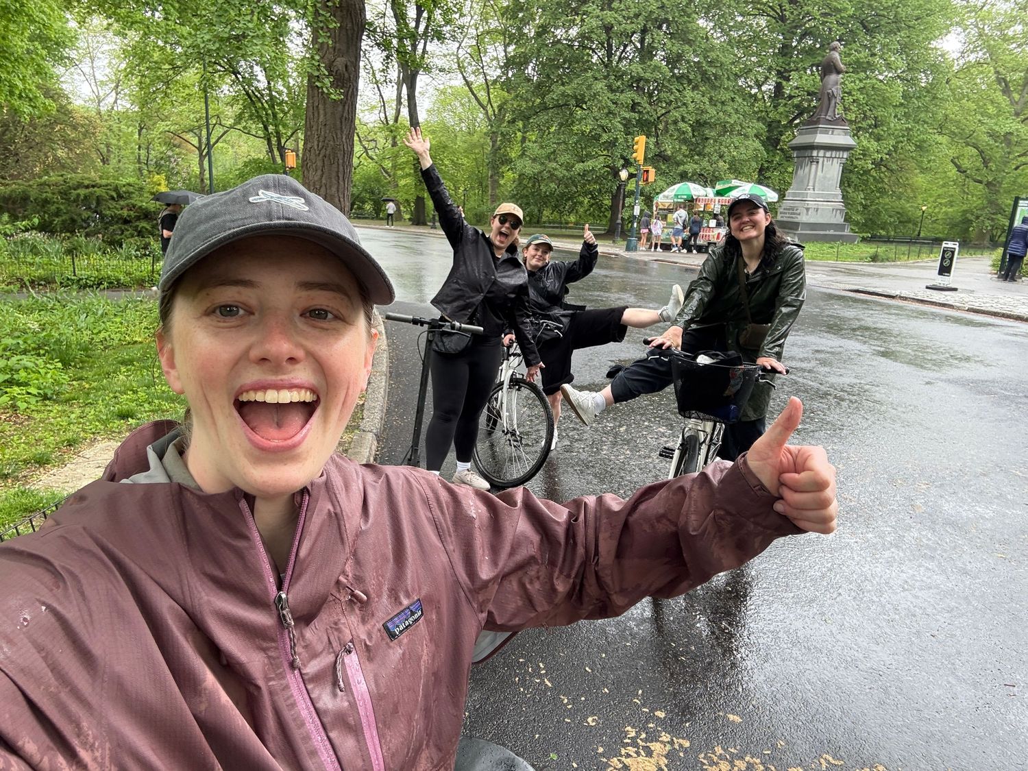 Person celebrating with raised arms on a rainy day in an outdoor park setting.
