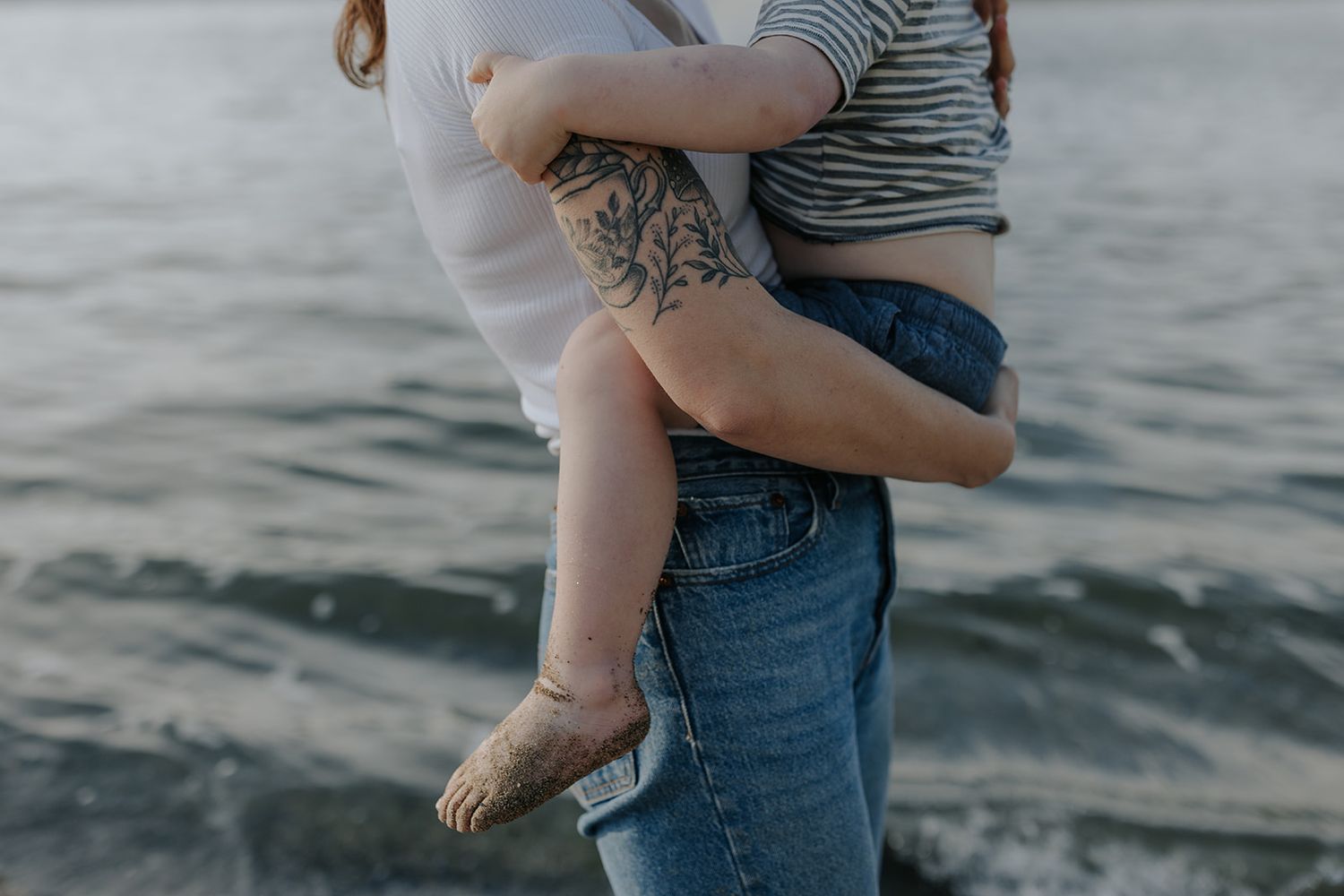 Couple sharing tender moments together near ocean at sunset.