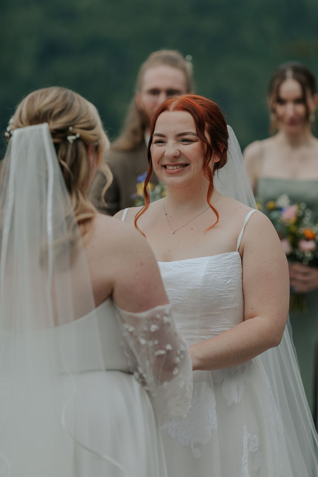 Wedding ceremony participants in white dresses standing together outdoors.