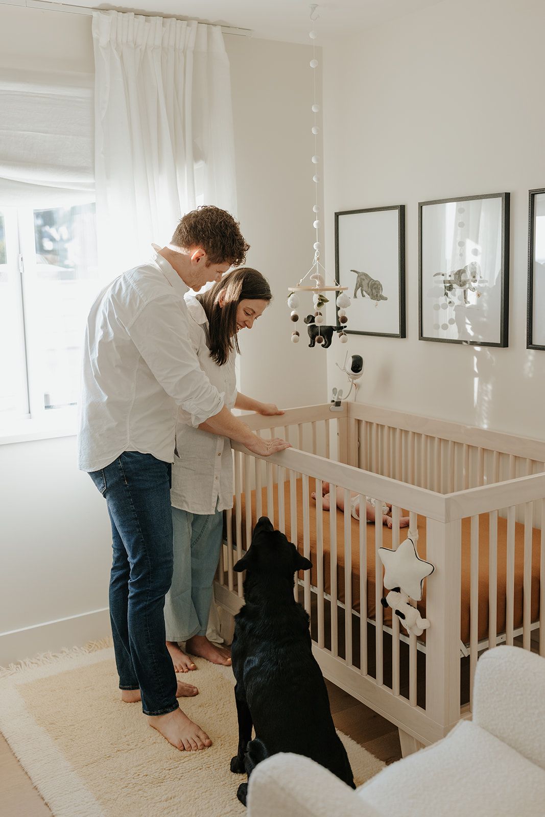 Modern nursery interior with white crib and people interacting with a dog.