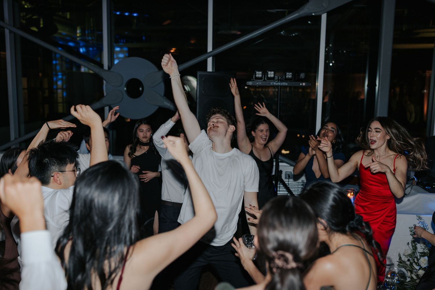 Energetic nightclub scene with silhouetted dancers raising their hands under dramatic lighting.