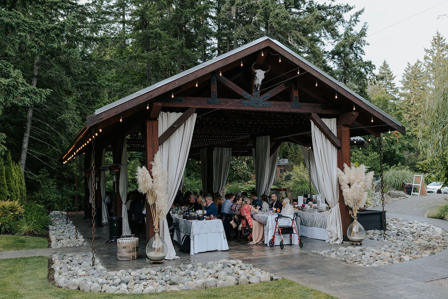 Rustic outdoor pavilion decorated for an intimate wedding reception among pine trees.