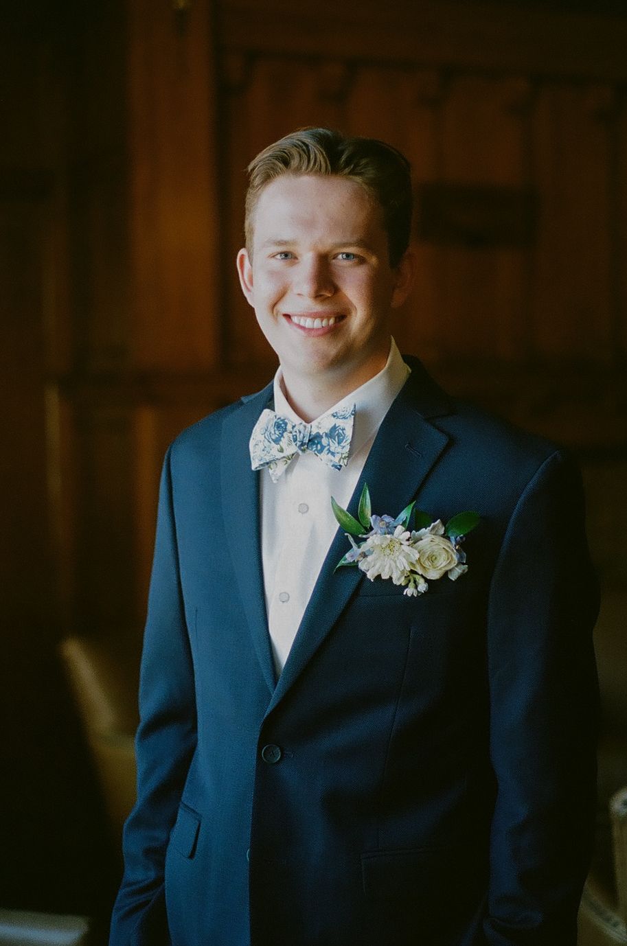 Groom in navy suit with bow tie and white boutonniere.