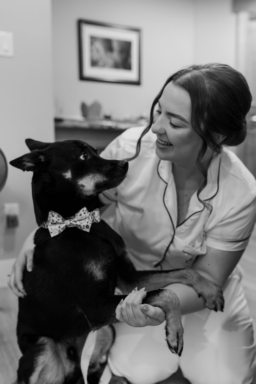 Sweet moment between person in white robe and black dog during wedding preparations.