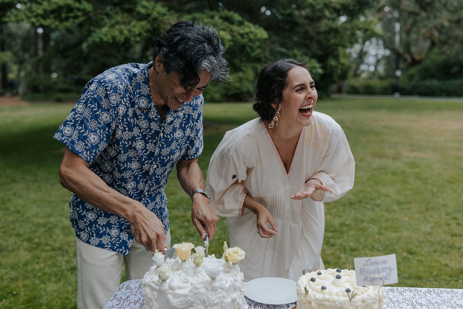Joyful moment during cake cutting at outdoor garden reception.