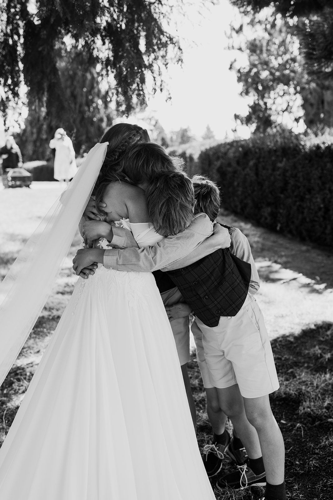Black and white photo of children playing around a white dress outdoors.