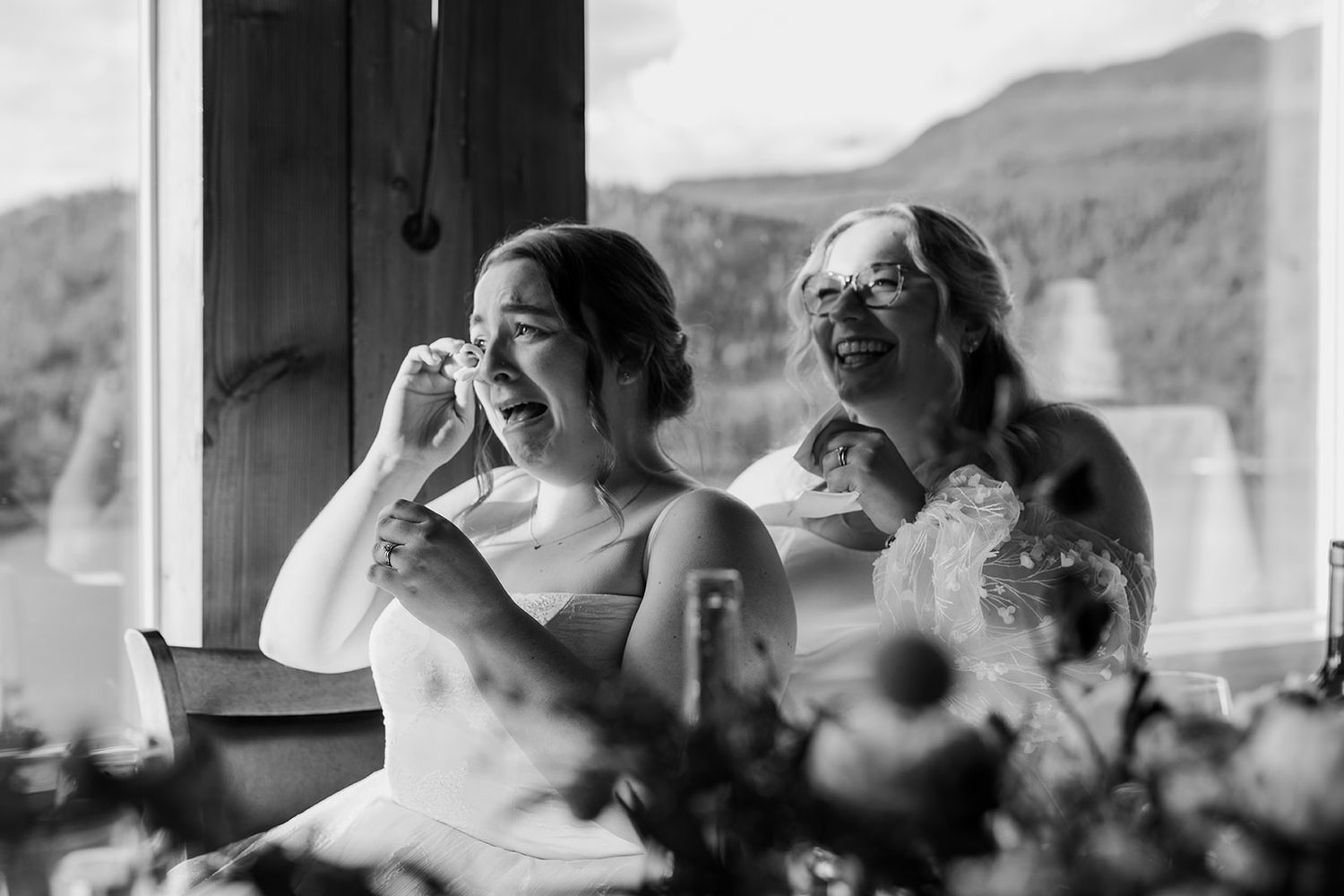 Black and white photo of wedding guests laughing during reception speeches.