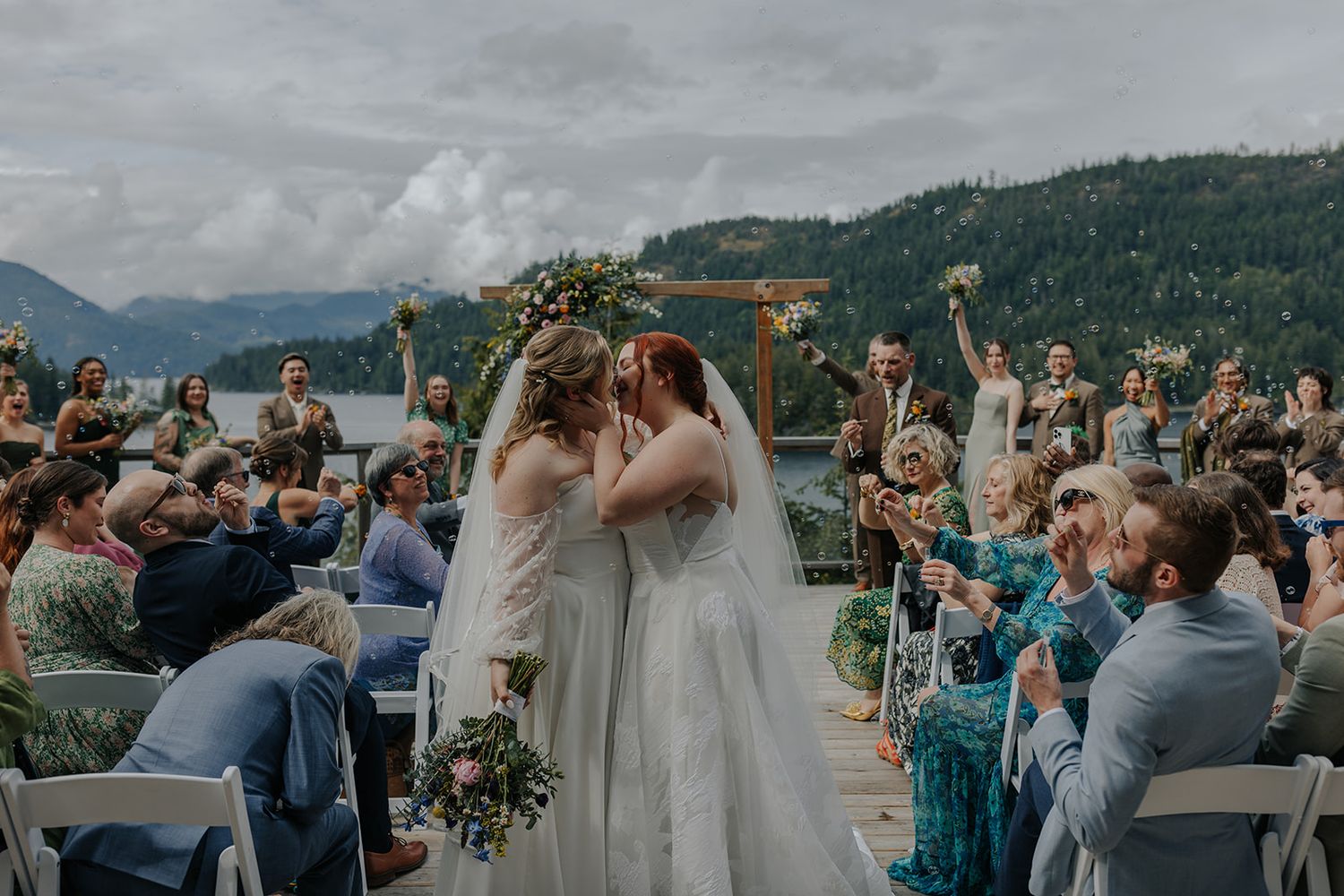 Outdoor wedding ceremony overlooking a scenic mountain landscape with guests in attendance.