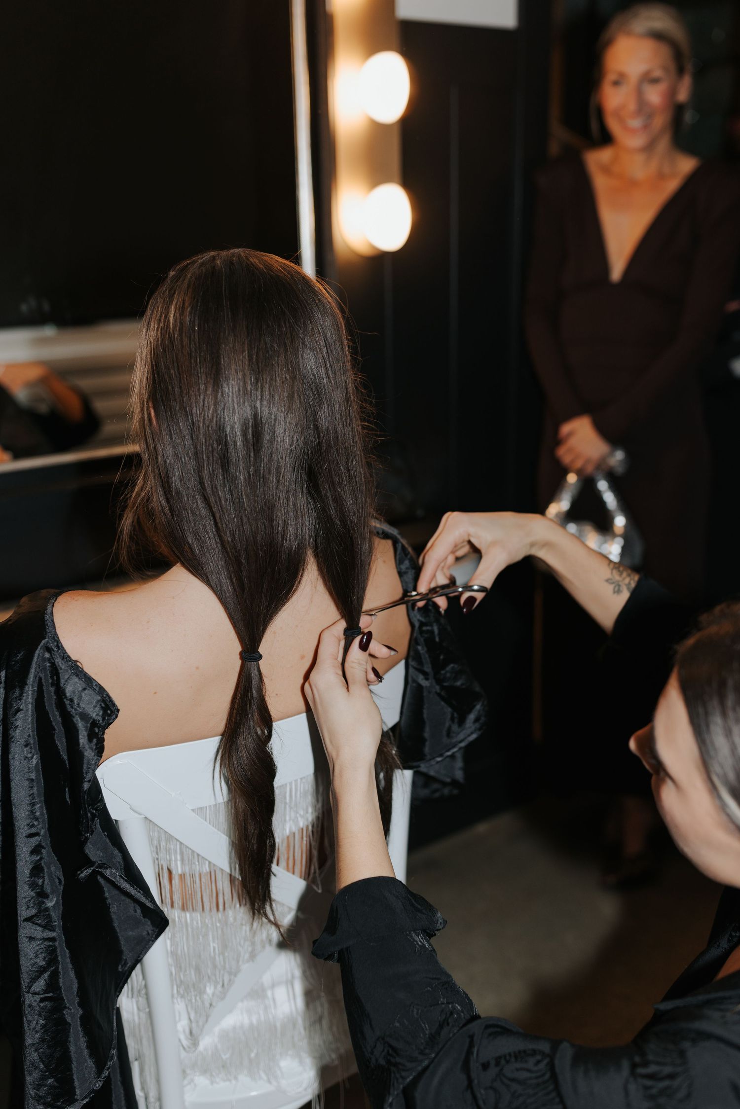 Behind the scenes preparation with stylists helping dress a bride in her wedding gown.