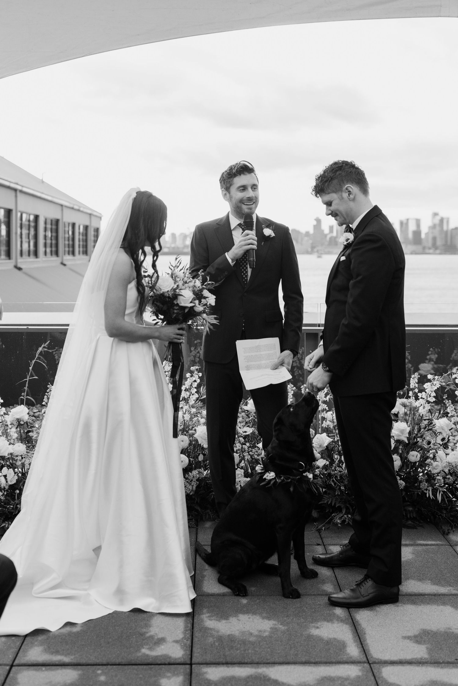 A wedding ceremony moment captured on an outdoor terrace with city views in the background.