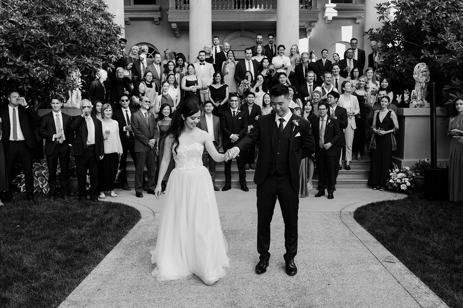 Black and white panorama of wedding guests celebrating during an outdoor reception.