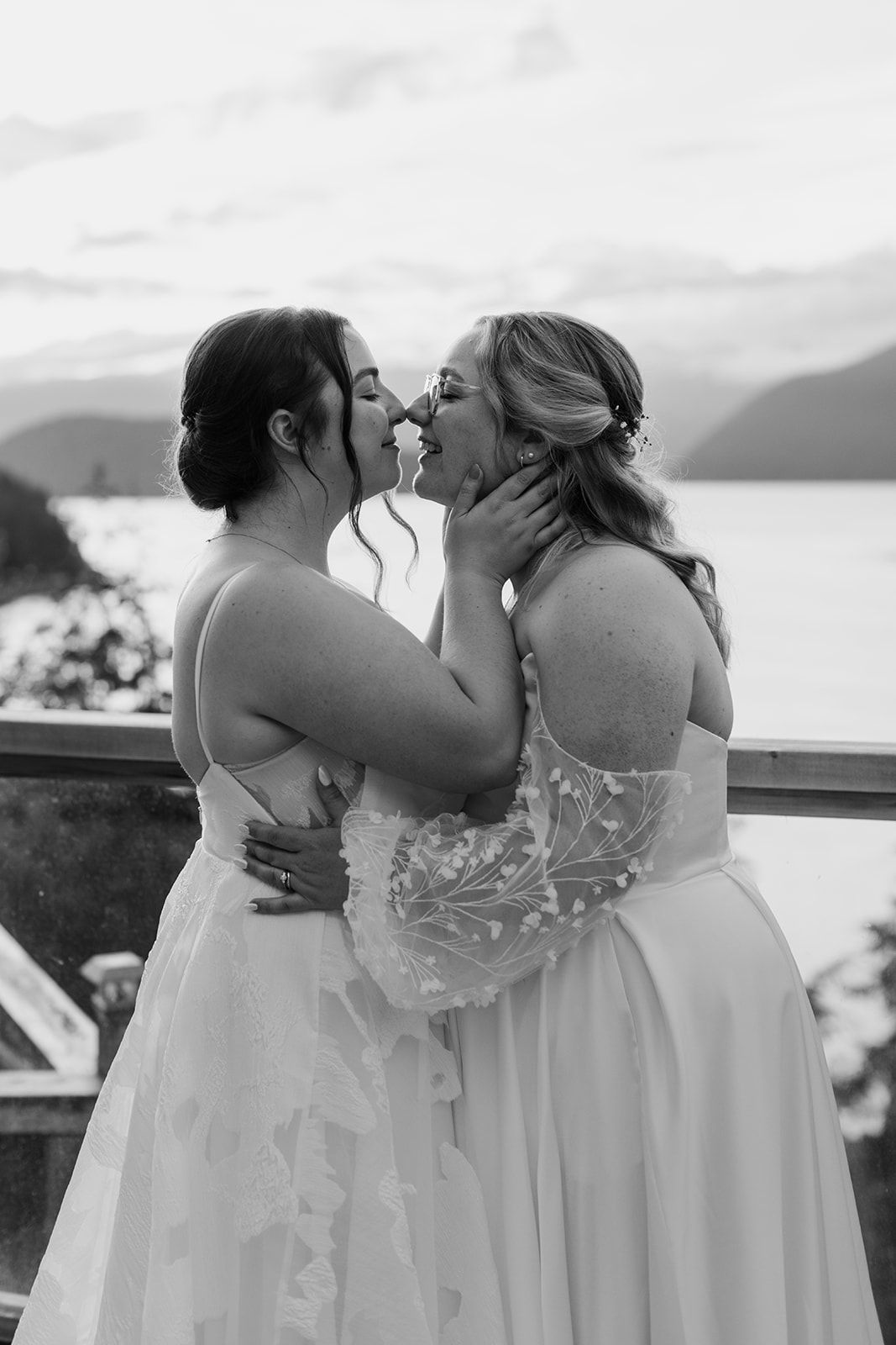 Black and white photo of couple sharing intimate moment at lakeside wedding venue.