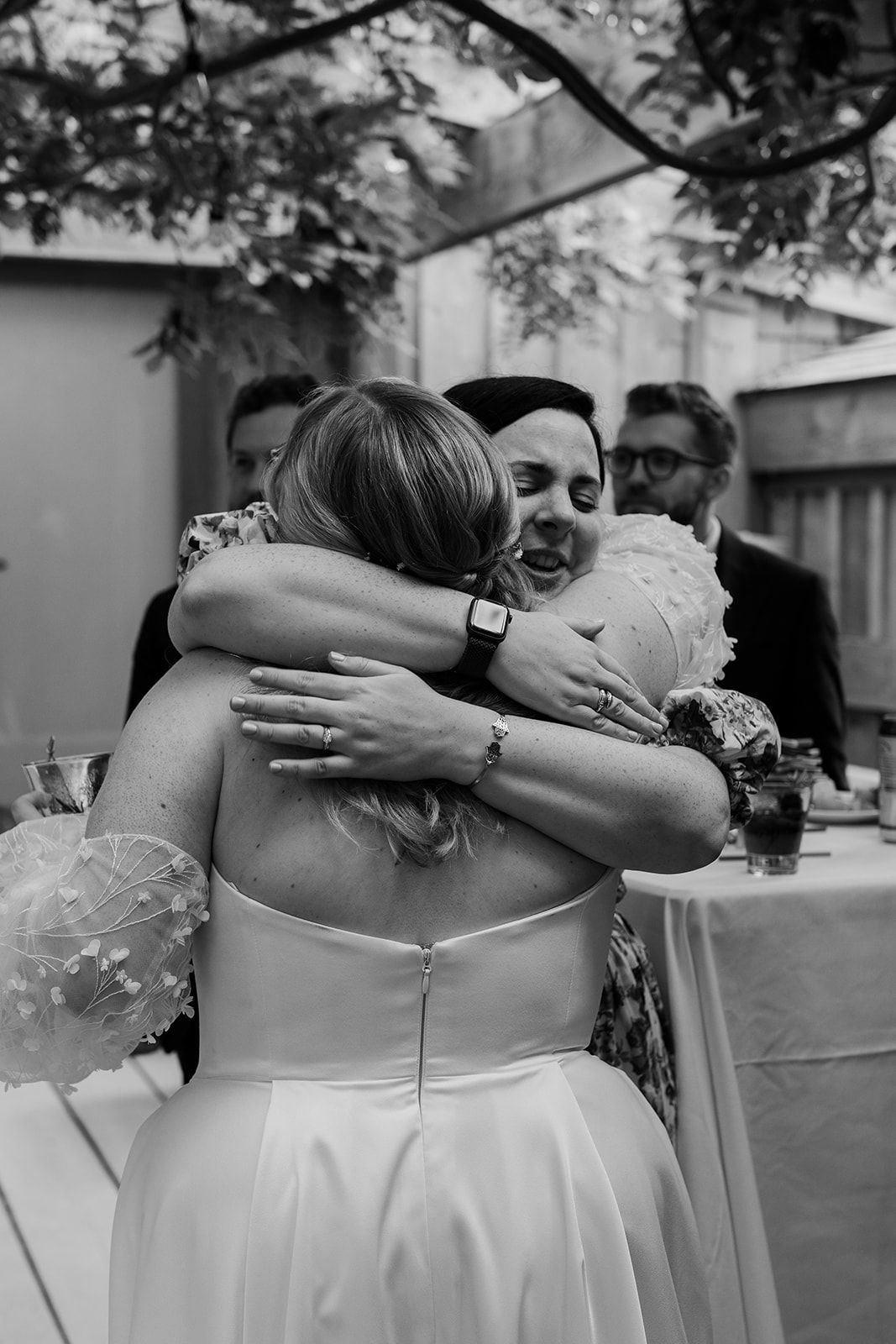 Black and white photo of emotional embrace during wedding celebration.