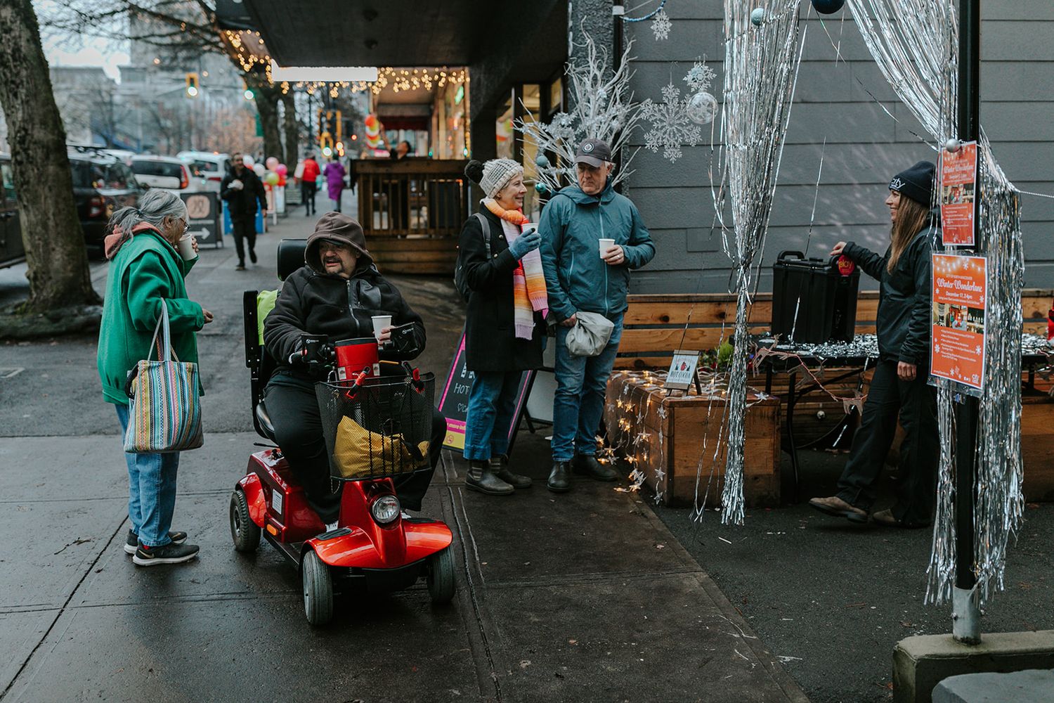Street performers and vendors gather on a busy urban sidewalk during daytime.