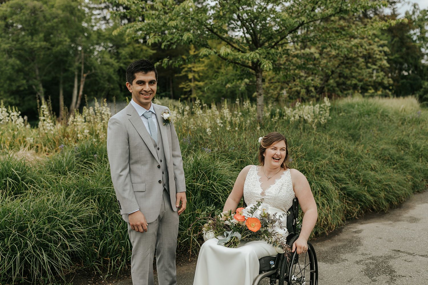 Wedding couple walking along a garden path surrounded by lush greenery.