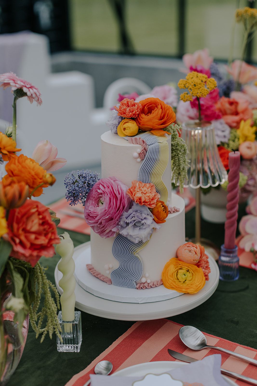 Elegant table setting with colorful floral centerpieces featuring pink, orange and coral blooms on white plates.