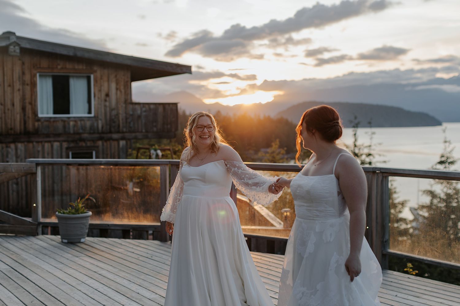 Wedding celebration at sunset overlooking a scenic mountain and water vista from a rustic wooden deck.