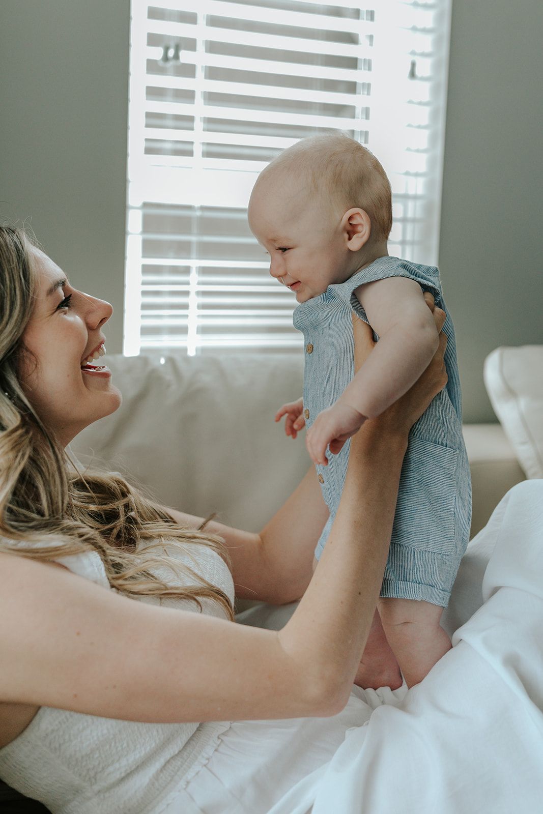 Tender moments between parent and baby on white couch in natural light.