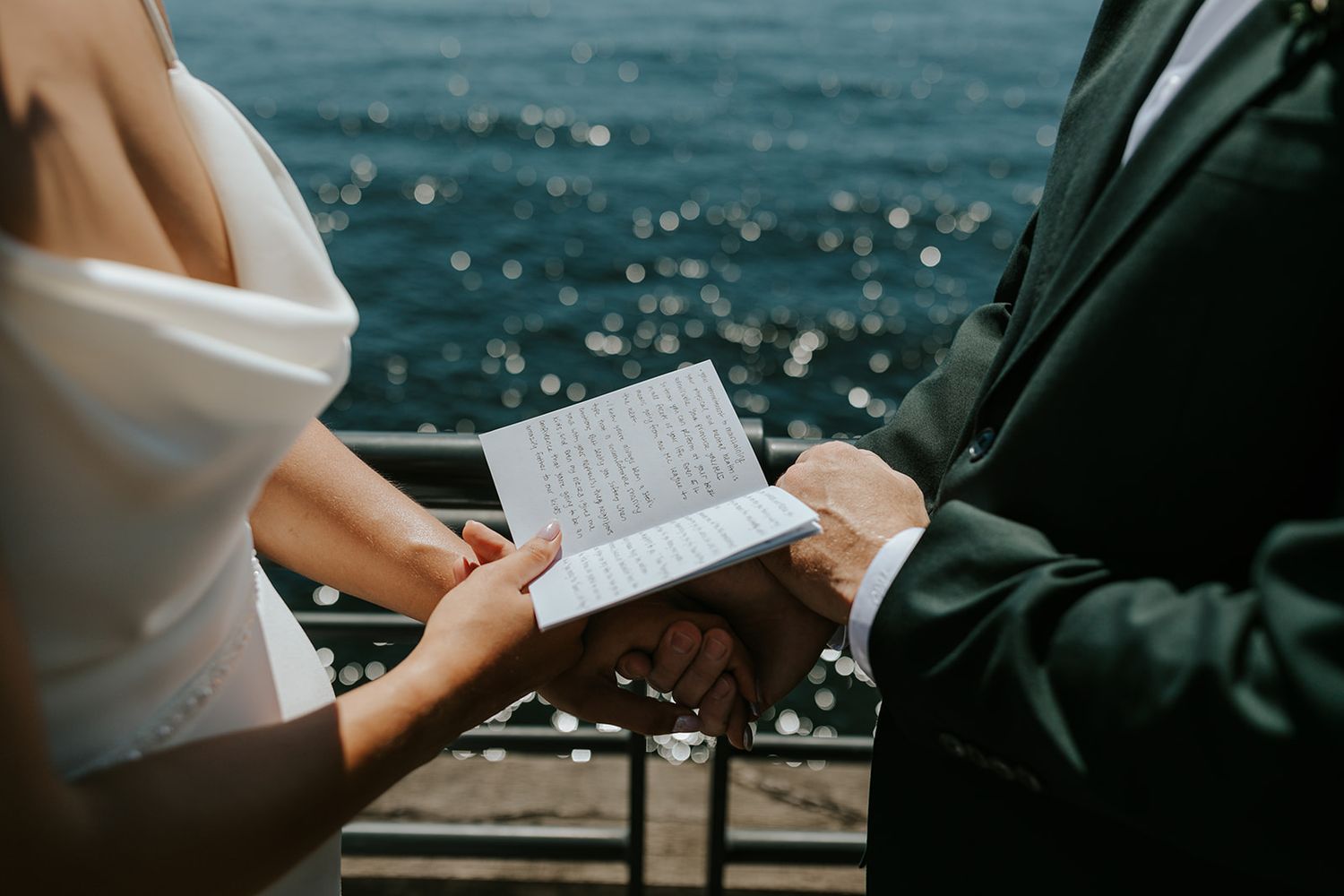 Close-up shot of hands writing in a notebook against a blurred outdoor background.