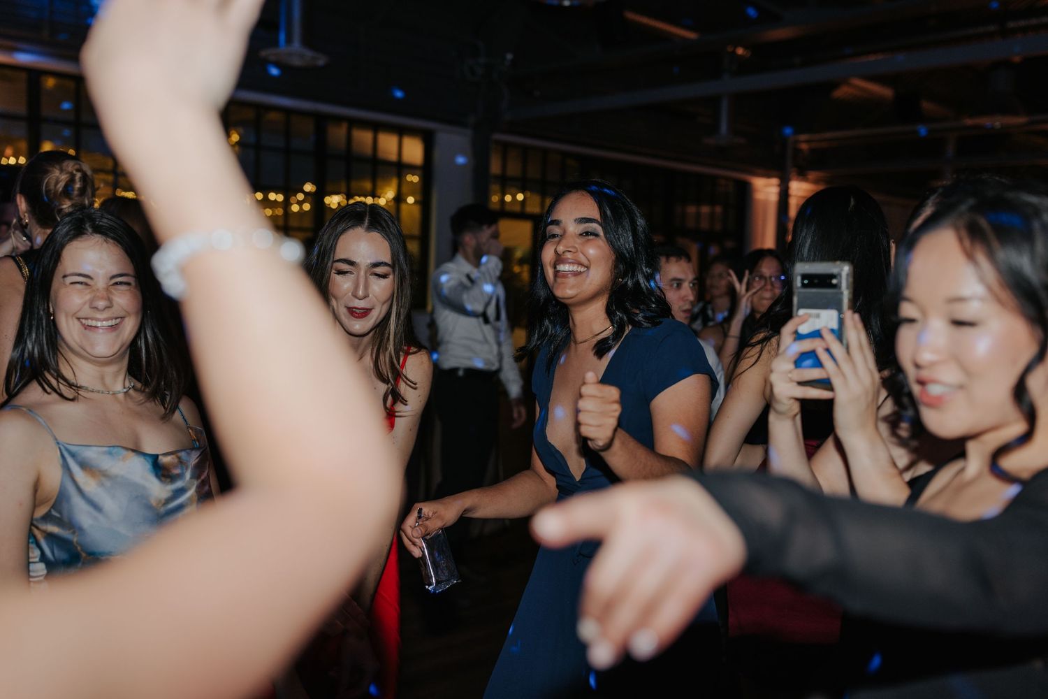 Crowd dancing and celebrating at a nighttime party with raised arms.