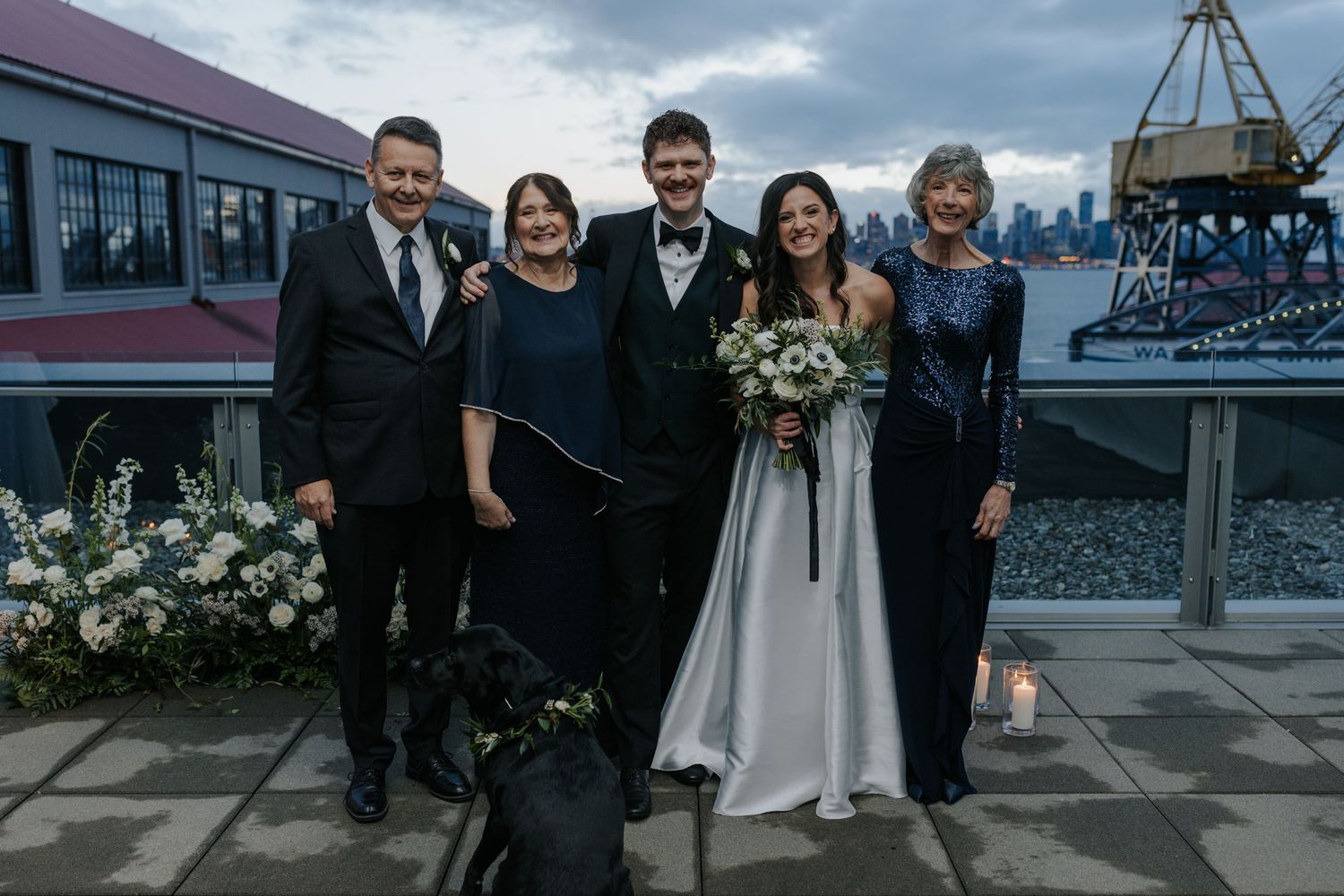 Wedding party walking together outside urban venue with cloudy sky backdrop.