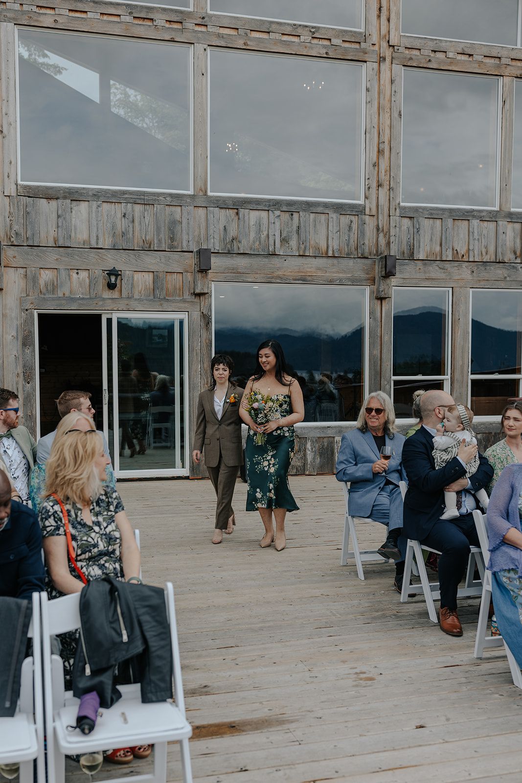 Wedding ceremony in a rustic venue with large windows overlooking mountain views.