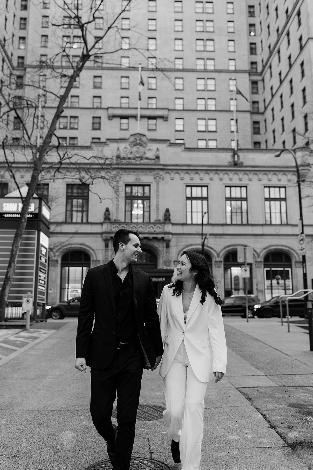 A couple walking and laughing together outside a grand historic building in the city.