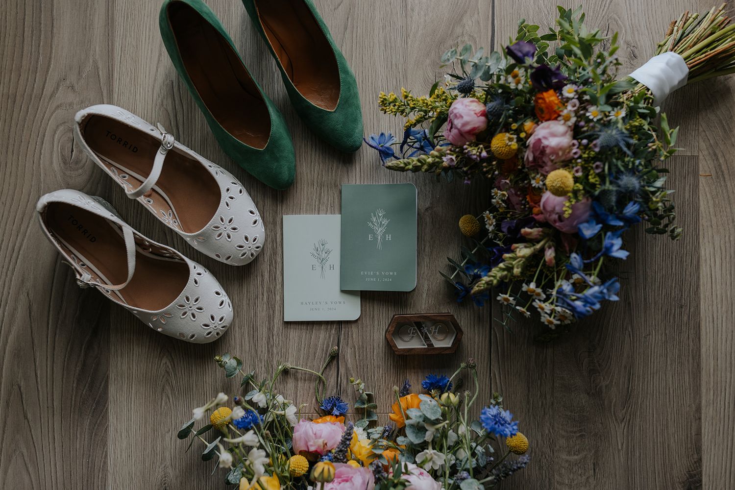 Wedding accessories including shoes, flowers and decor arranged on wooden flooring.