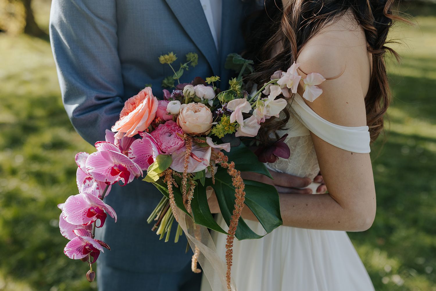 Wedding couple holding pink and white floral bouquets during outdoor ceremony.