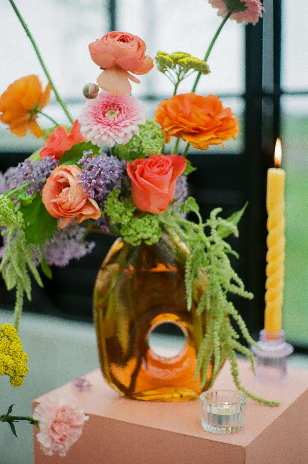 Colorful floral centerpieces with orange and pink blooms in amber glass vases.