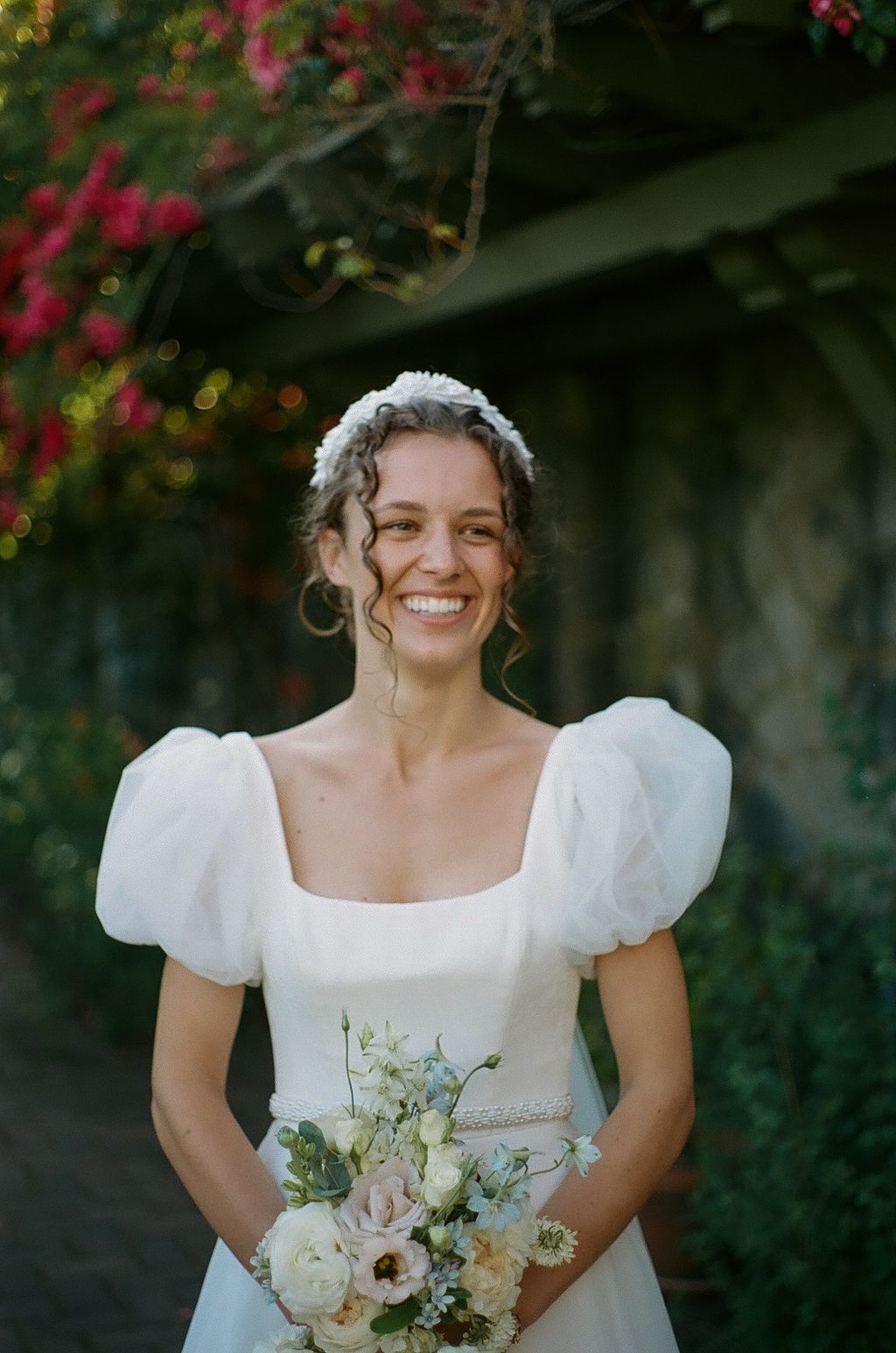 A bride in a classic white dress with puff sleeves holds a delicate bouquet.