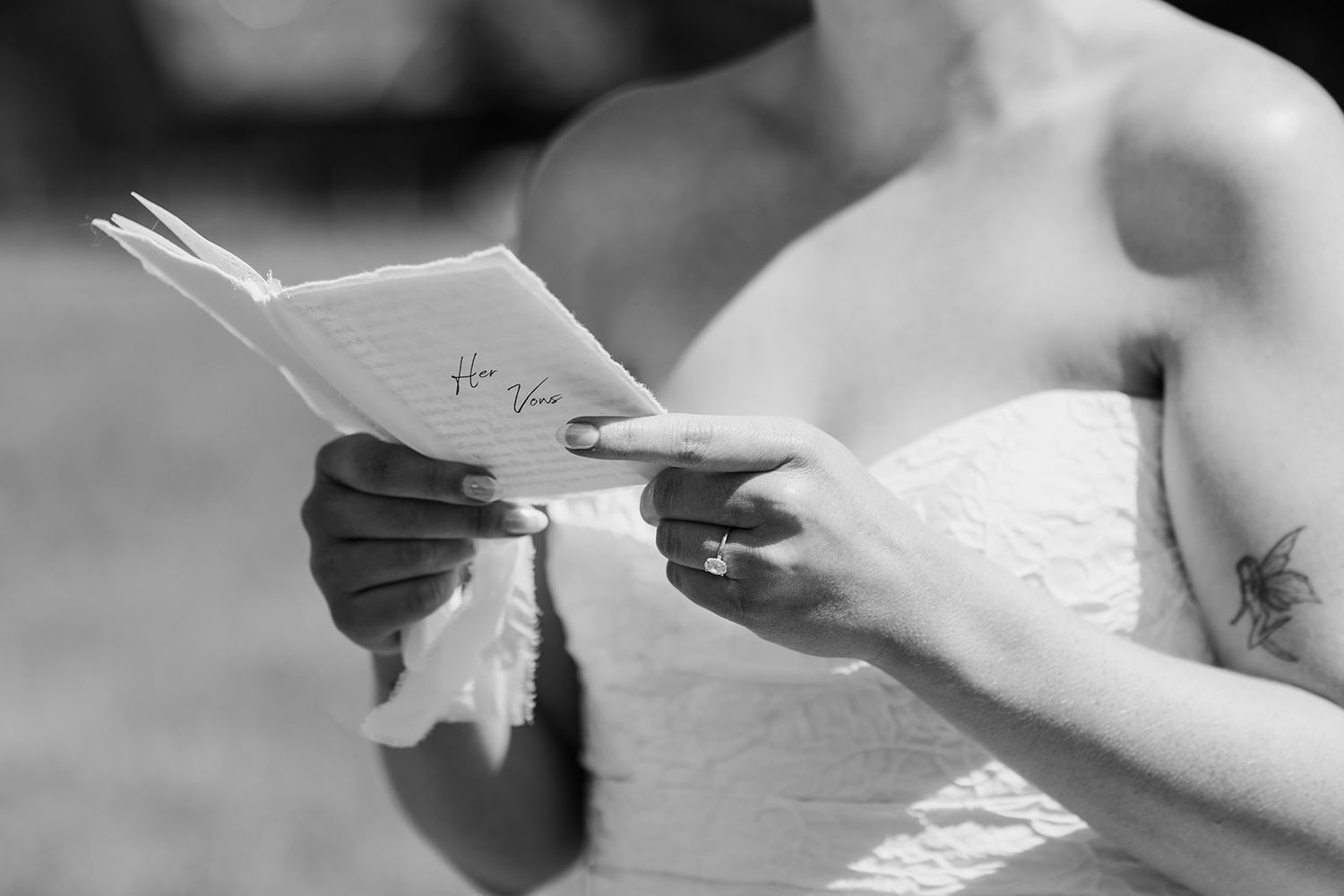 Black and white image of hands exchanging wedding vows on paper.