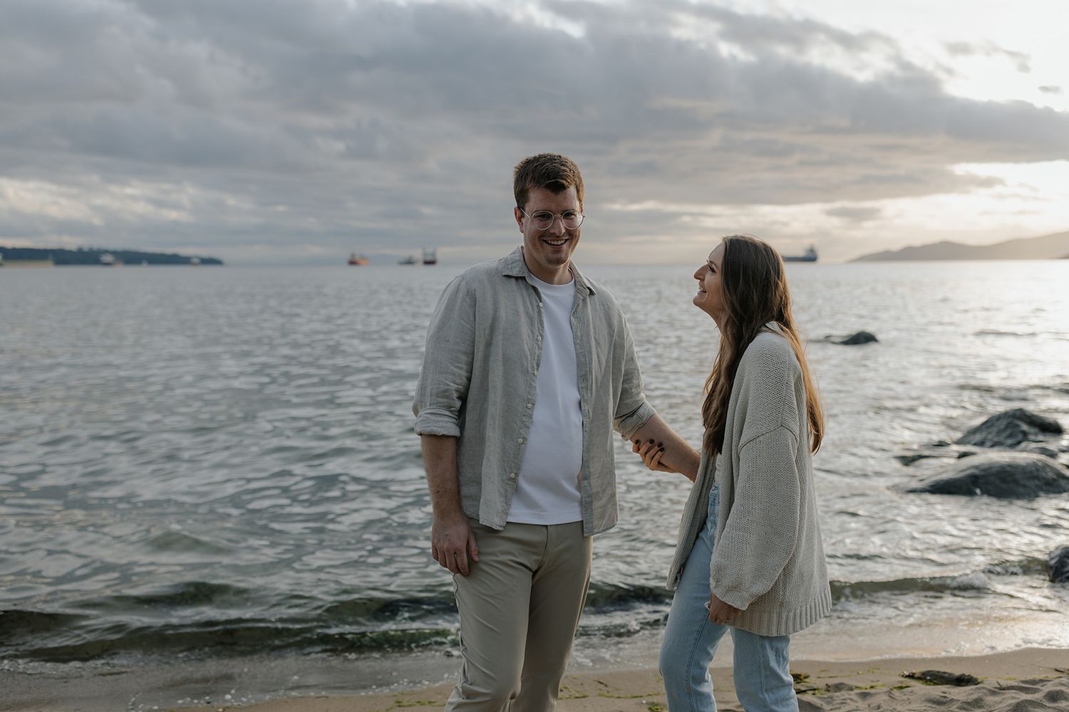 Romantic sunset photoshoot of a couple walking along a scenic coastal shoreline.