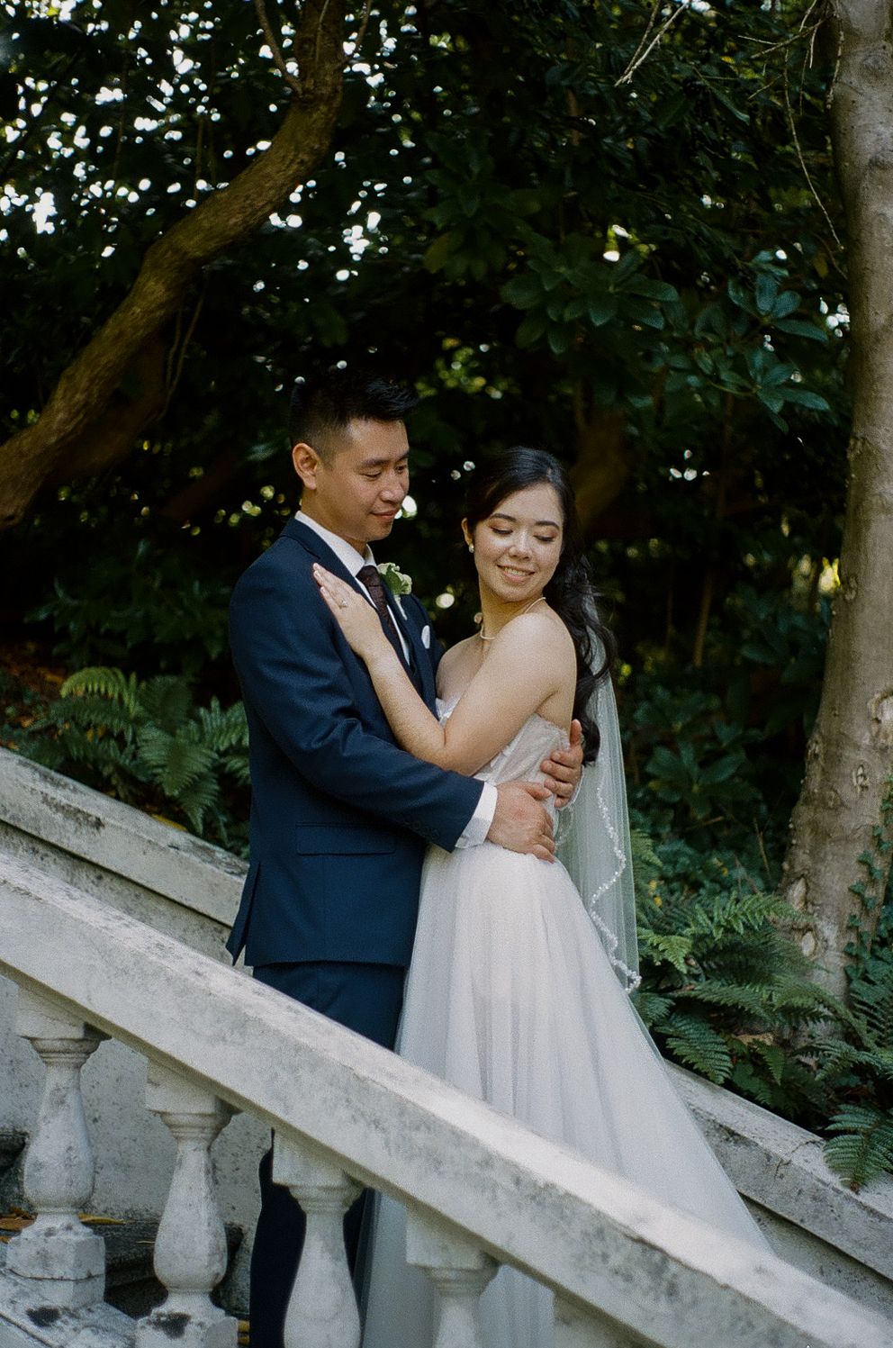 Romantic moment on outdoor stone staircase surrounded by lush greenery.