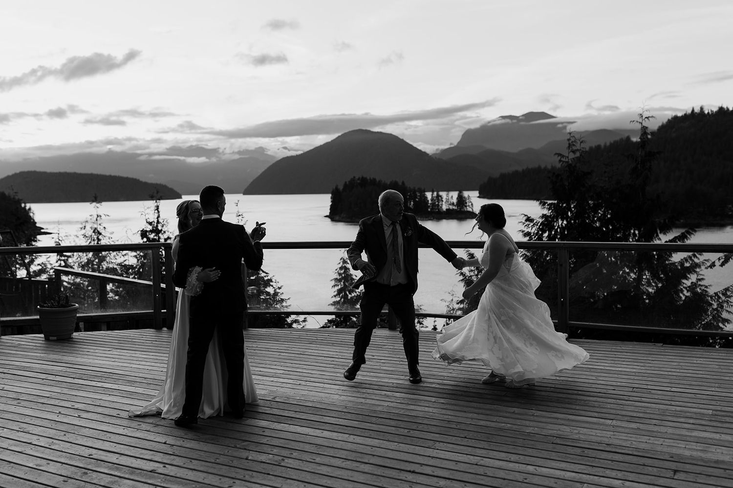 Black and white silhouette of a wedding dance against a mountain backdrop at sunset.