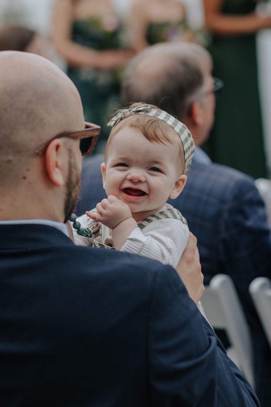A smiling baby in formal attire at a wedding celebration.