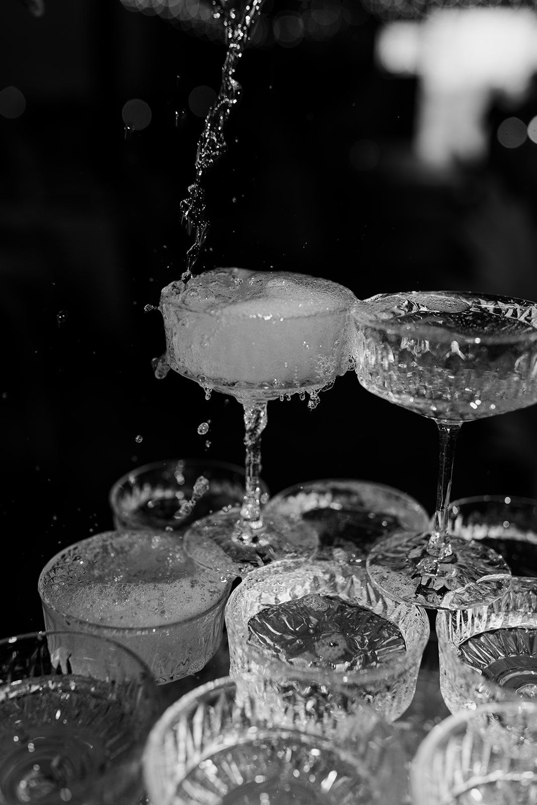 Champagne being poured into a tower of stacked crystal glasses creating a sparkling cascade effect.
