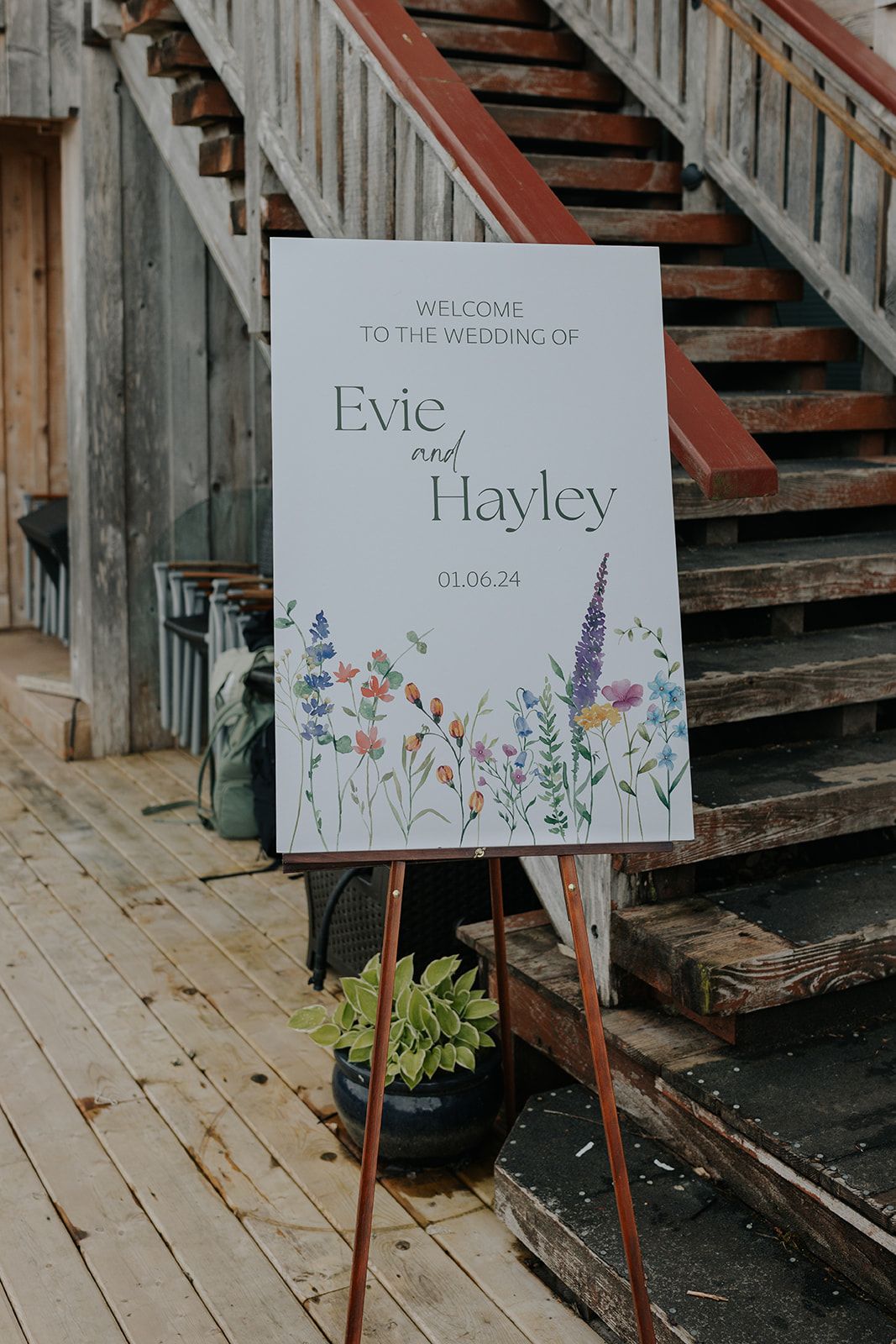 Watercolor floral welcome signs displayed on wooden easels at a rustic wedding venue.