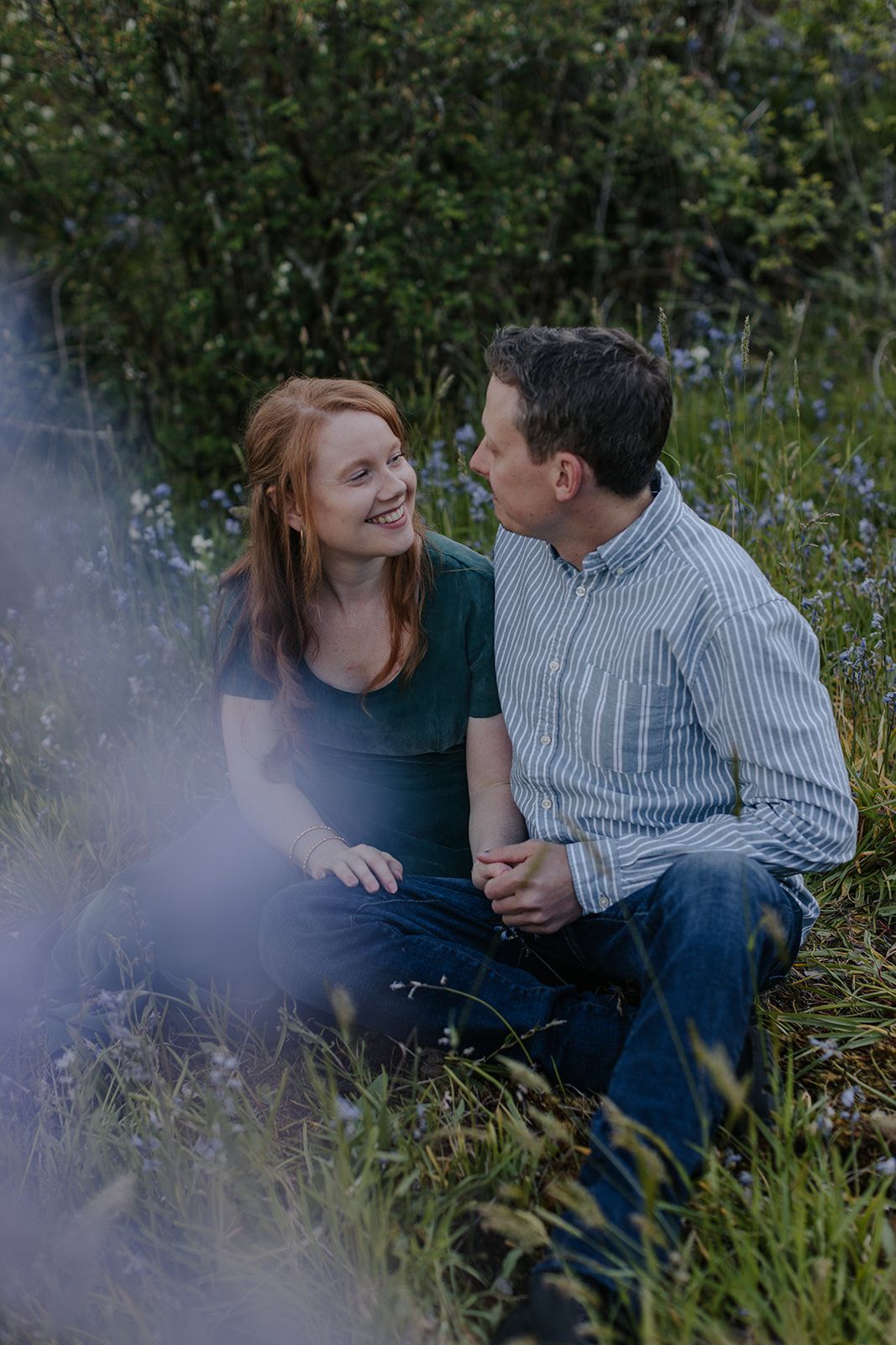 A couple shares intimate moments while sitting in a field of wildflowers.