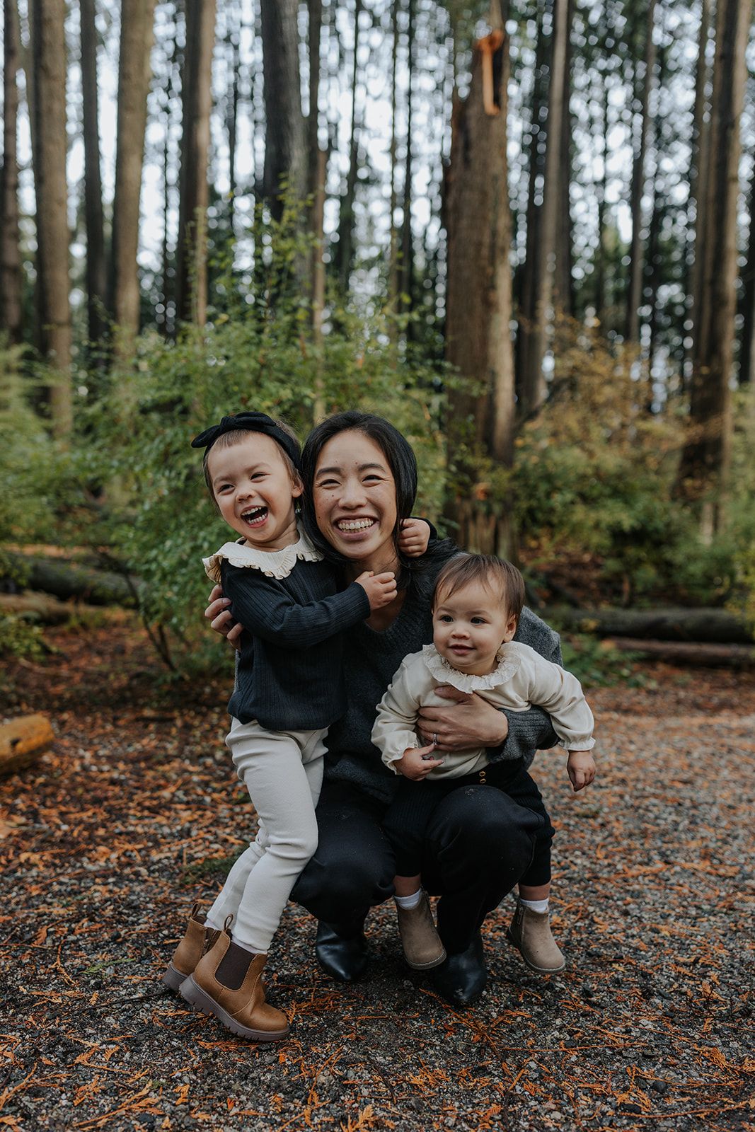 Family enjoying playful moments together on fallen leaves in an autumn forest.