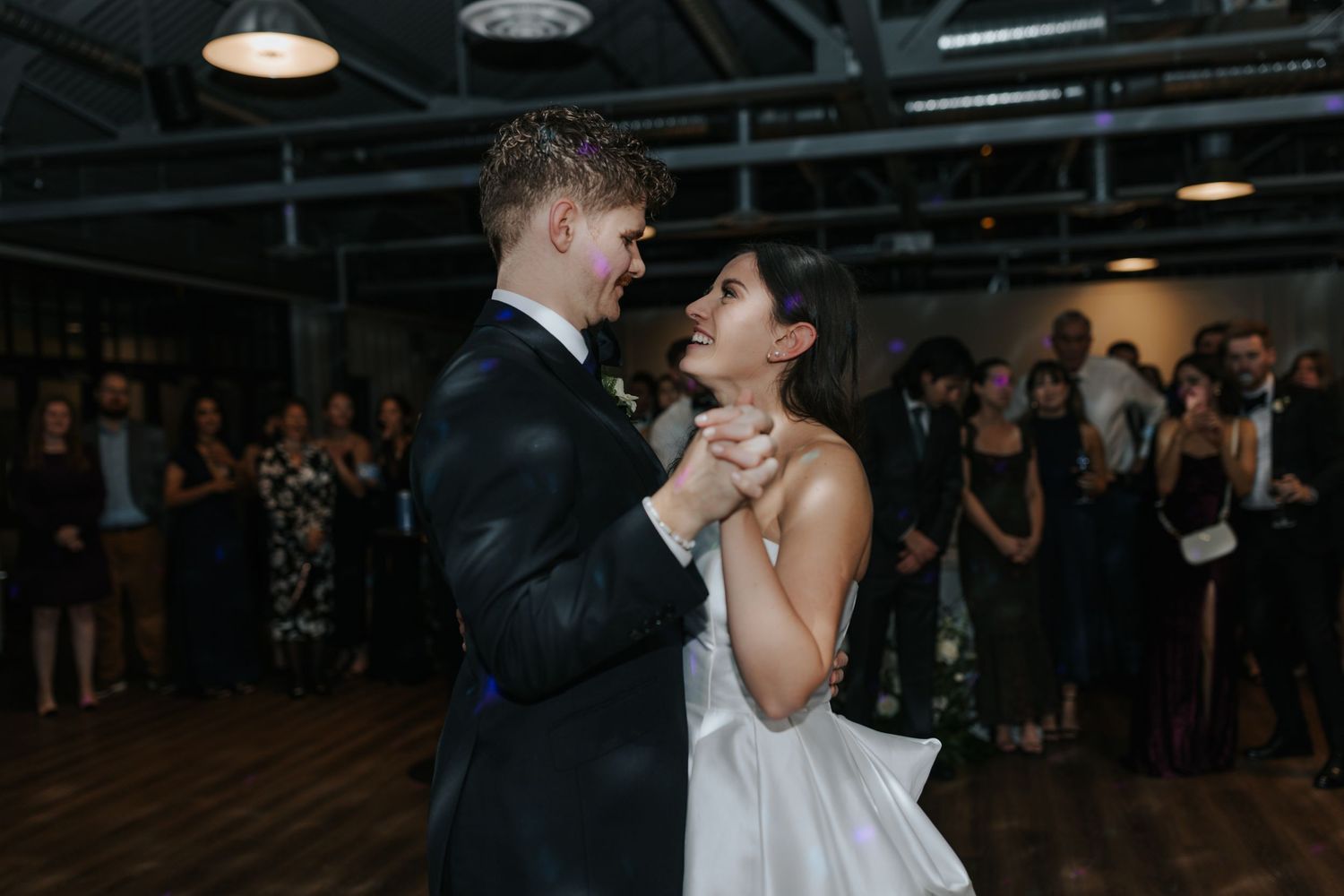 Wedding guests dance and celebrate during an indoor reception party.