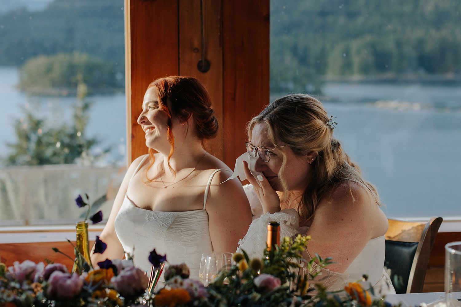 Wedding reception venue with scenic lake and mountain backdrop through windows.