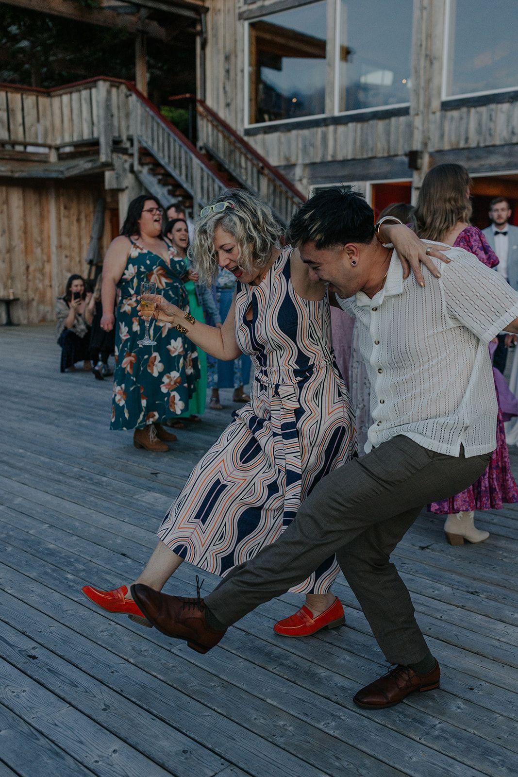 Energetic dance moves being performed on a rustic wooden deck during a celebration.