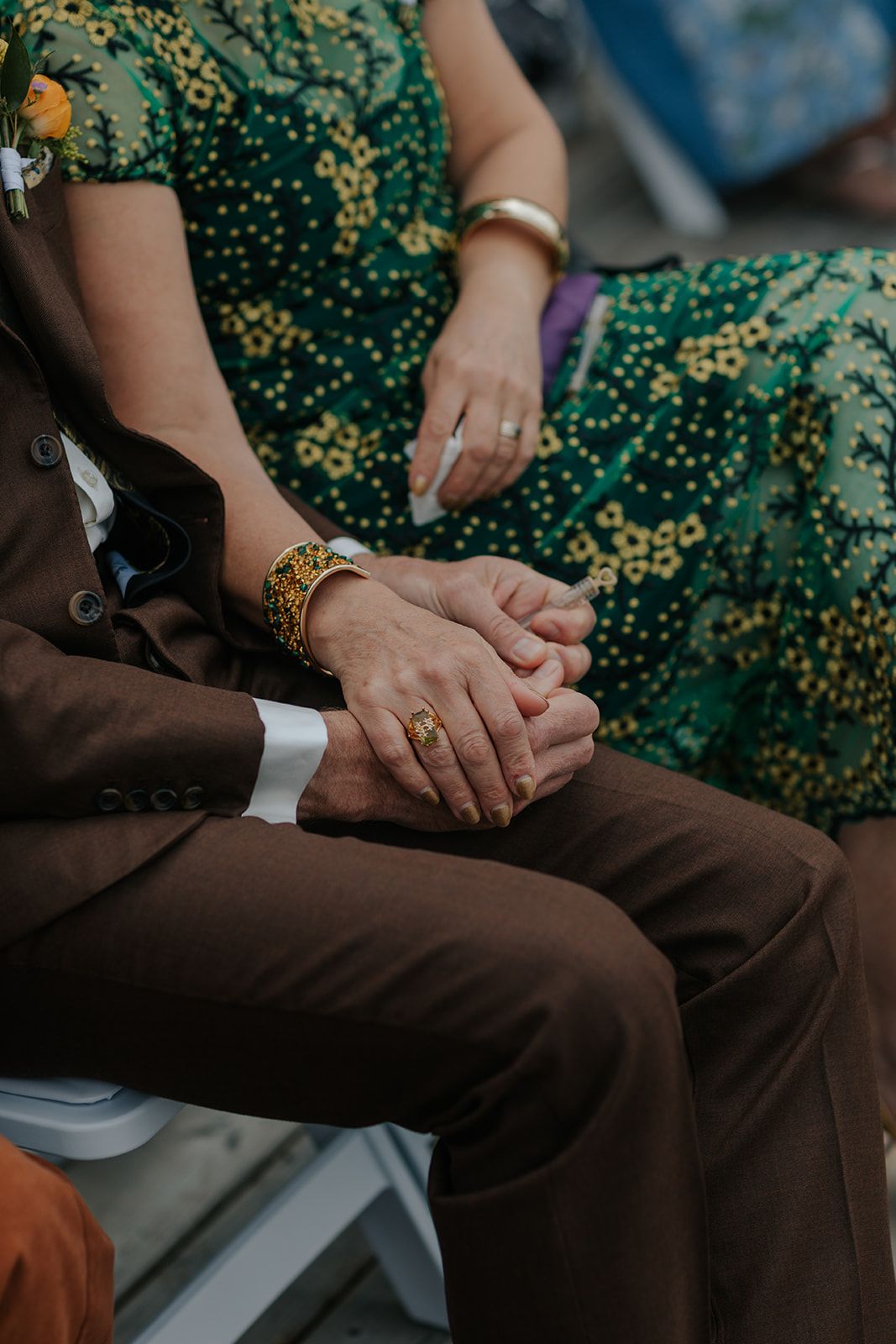 Wedding guests in formal attire seated with green floral patterns visible.