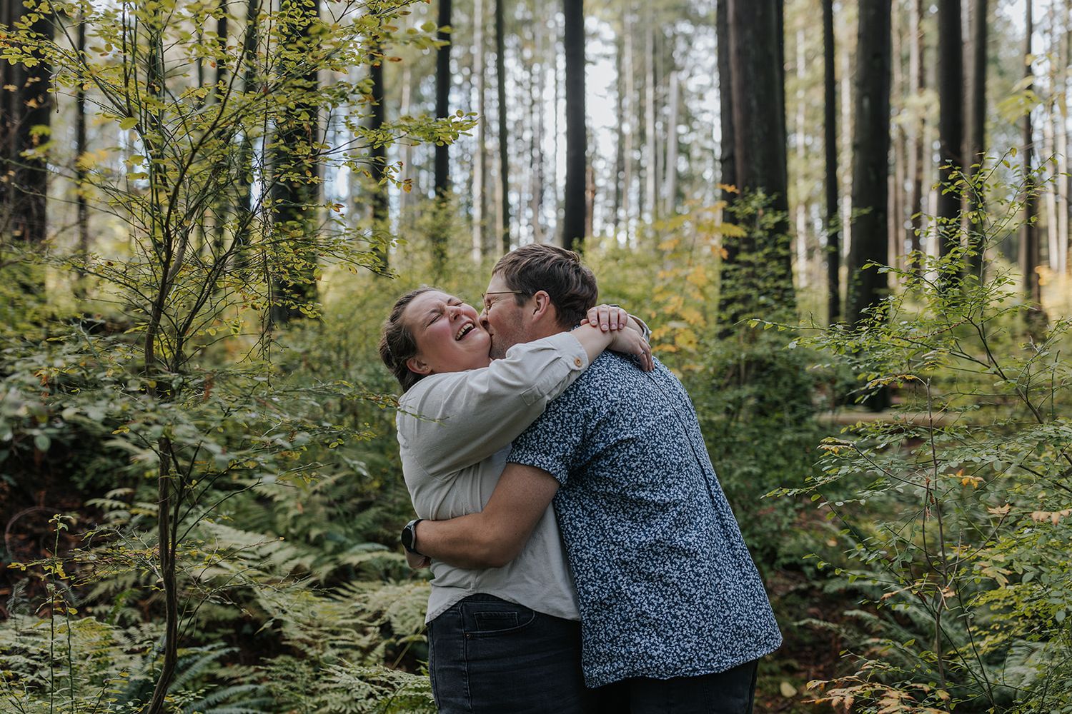 Candid moments of a couple embracing and laughing together in a wooded outdoor setting.