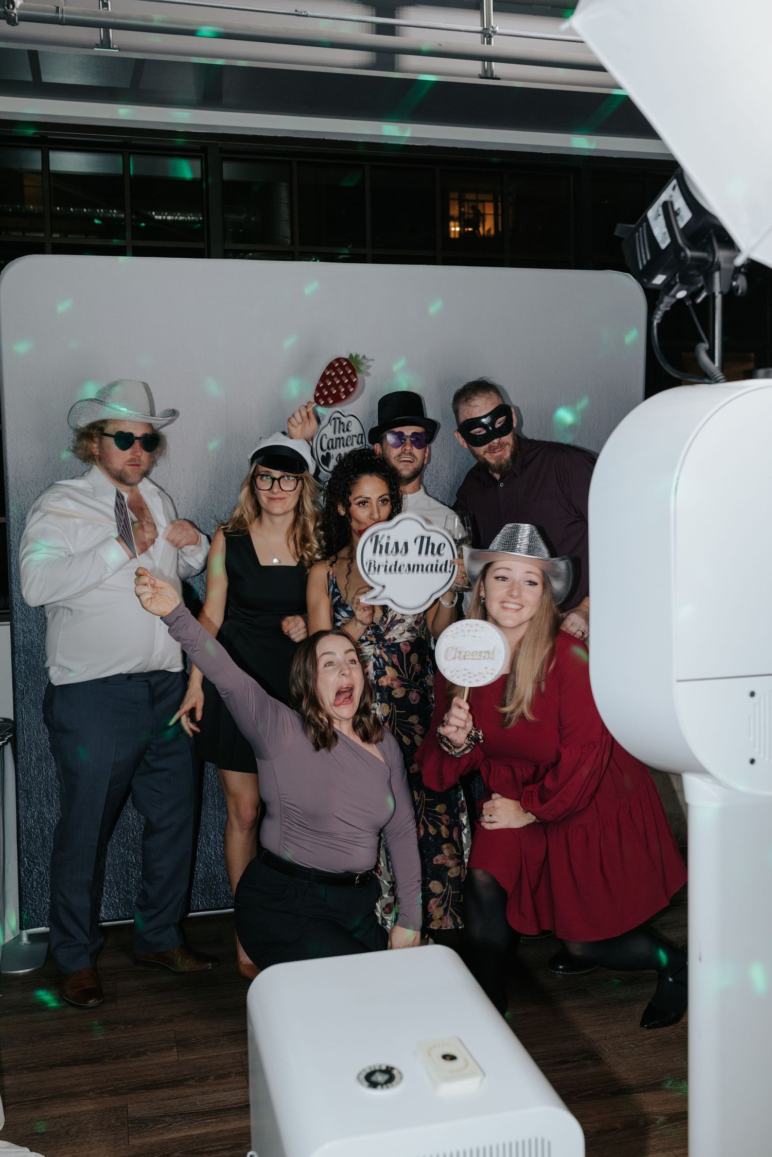 Party guests dancing and celebrating in a lively group setting with decorative lighting.