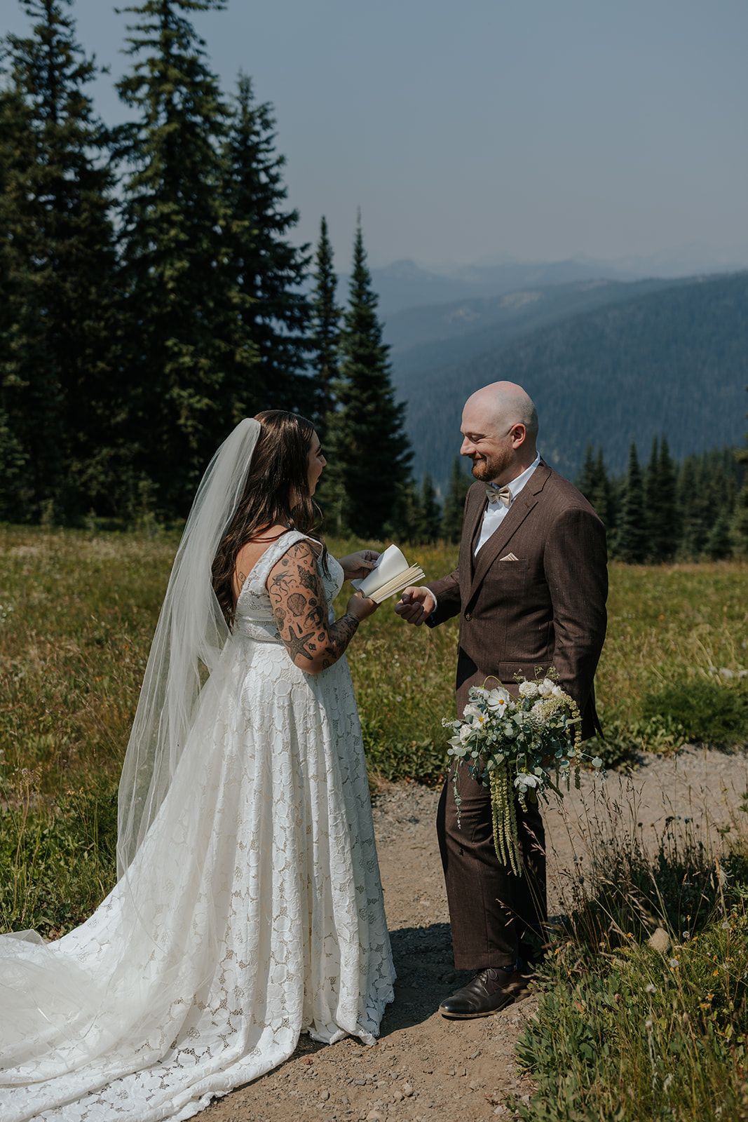 Wedding couple sharing intimate moments on a mountain trail with evergreen trees in background.