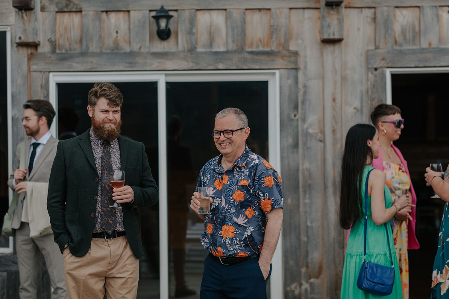 Wedding guests mingling and socializing at rustic outdoor venue.