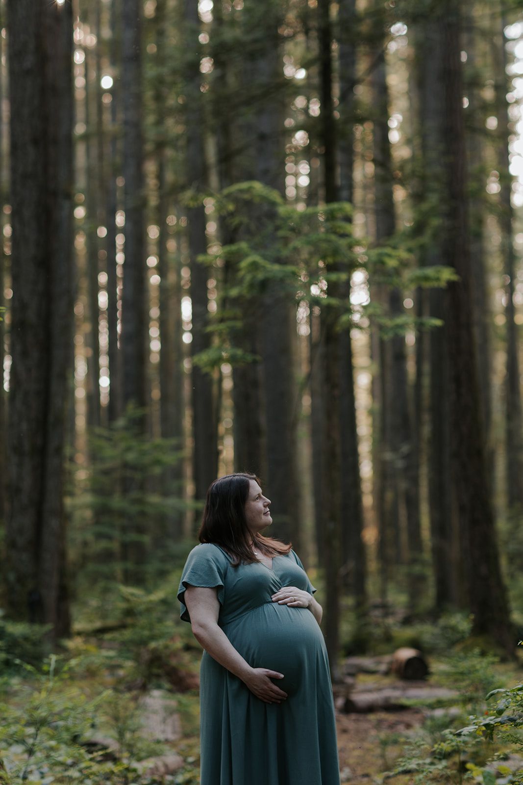 Couple embraces tenderly in a lush green forest setting during an intimate outdoor photoshoot.
